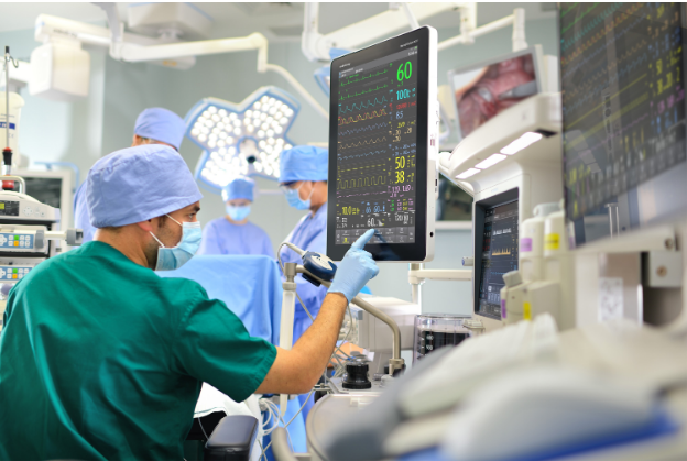 A Surgeon within an operating room checking patient vitals on a screen